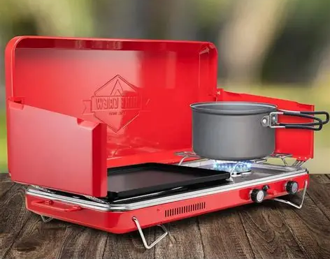 Hike Crew 2 in 1 Gas Camping Stove and Griddle on a camp table with bacon and pancakes cooking, surrounded by morning sunlight in the forest.