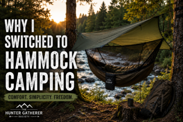 Forest hammock camping setup beside a river during golden hour with tarp shelter and backpack
